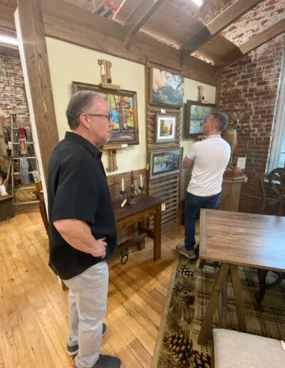 Two men viewing artwork in a cozy gallery interior.