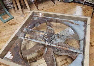 Antique metal windmill blades displayed in wooden frame.