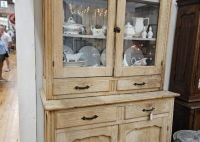 Wooden cabinet with glass doors displaying white dishes.